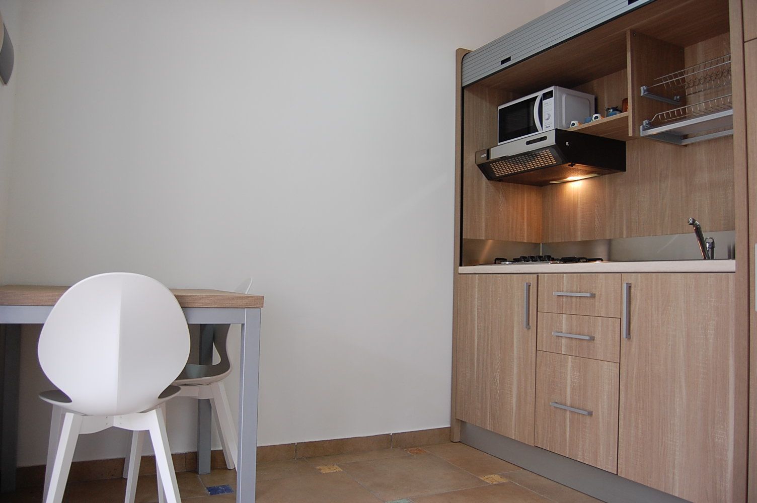 Une cuisine de taille réduite, équipée d’un four à micro-ondes, d’une cuisinière et de meubles de rangement en bois.