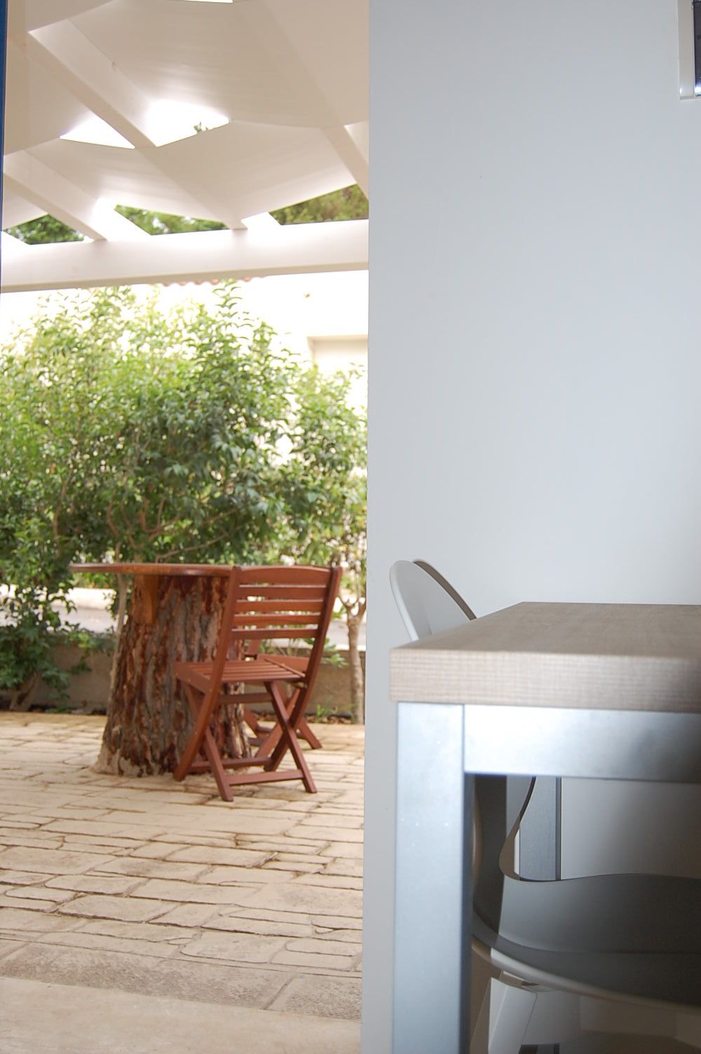 Un patio al aire libre con mesa y sillas de madera, un árbol y vistas a zonas verdes.