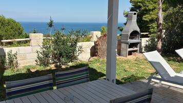 Un patio con tavolo e sedie, un muro in pietra e vista sul mare.