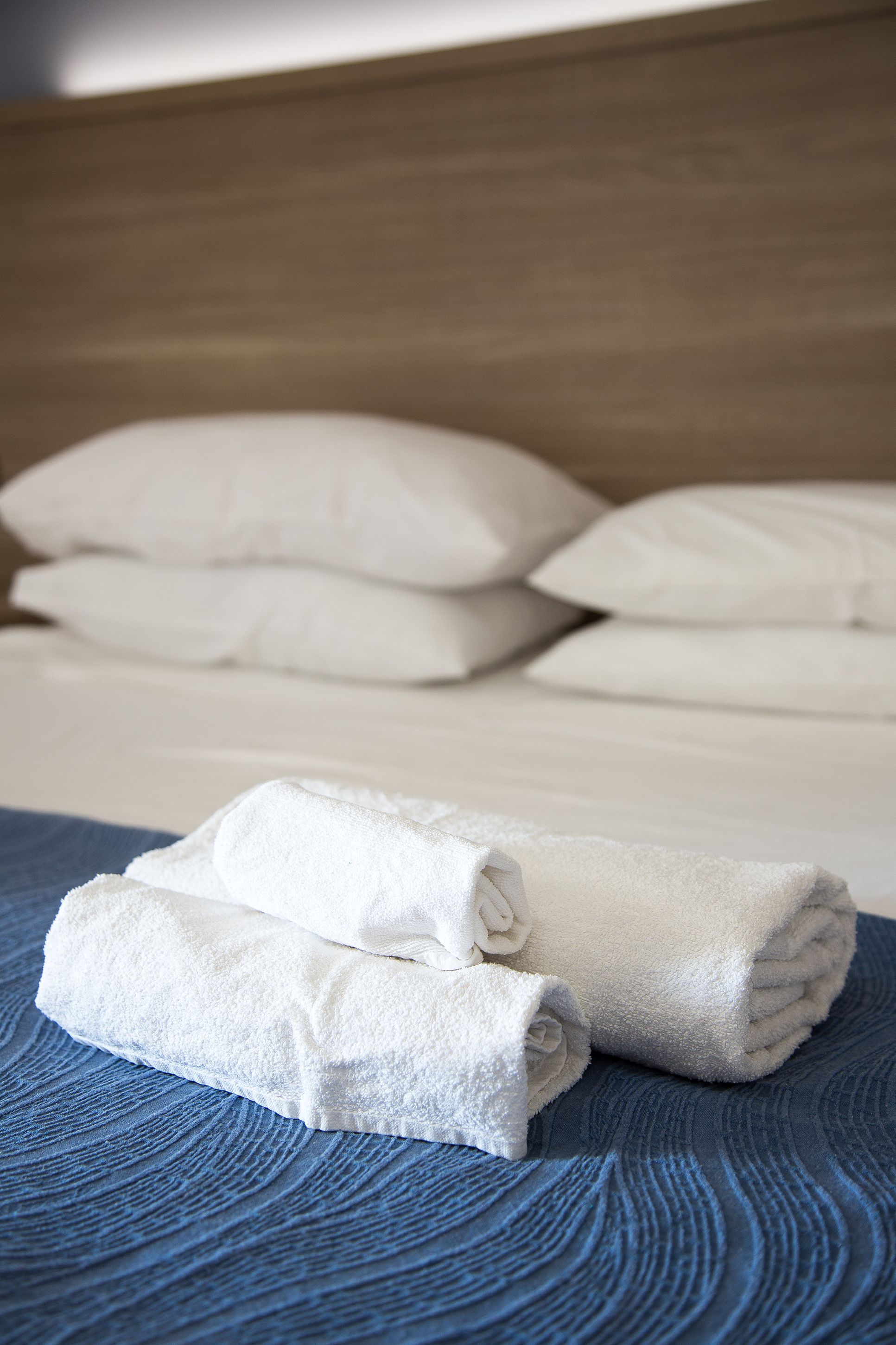 A neatly made bed with white pillows and folded towels.