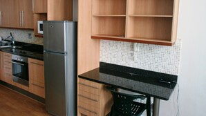 Eine Küche mit Holzausstattung, einem Edelstahlkühlschrank und einer gefliesten Spritzschutzwand.