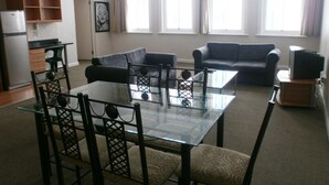 Ein Wohnzimmer mit einem Glastisch, zwei Sofas und einem Fernseher.