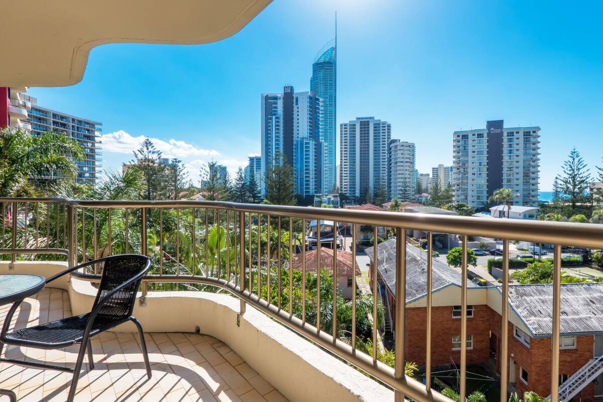 A balcony with a view of a cityscape, including tall buildings and a clear sky.