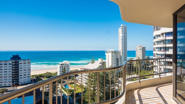 Un balcone con vista sull'oceano e sulla spiaggia, circondato da edifici alti.