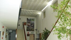 A staircase leading to a door with a sign above it. There are potted plants and a wall with framed pictures. - El Faisan C&R Hotel (Arcos de la Frontera)