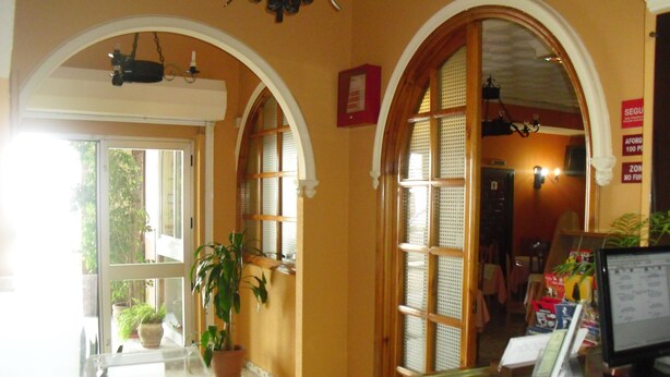 A reception area with arched doorways, a reception desk, a computer, and potted plants. - El Faisan C&R Hotel (Arcos de la Frontera)