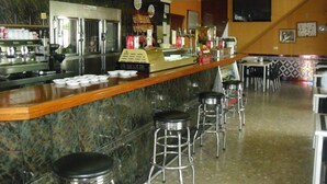 A restaurant with a marble counter, stainless steel appliances, and bar stools. - El Faisan C&R Hotel (Arcos de la Frontera)