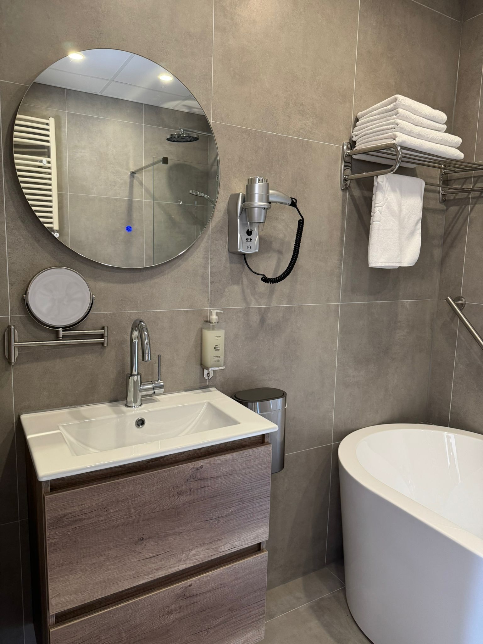 A bathroom with a sink, mirror, towel rack, and a bathtub.