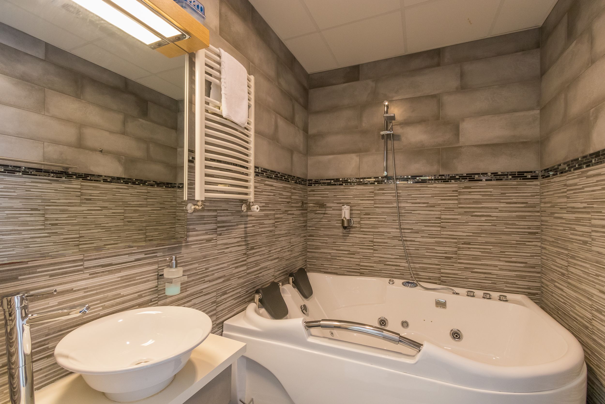 Een badkamer met een bad, een wastafel en een handdoekhouder.