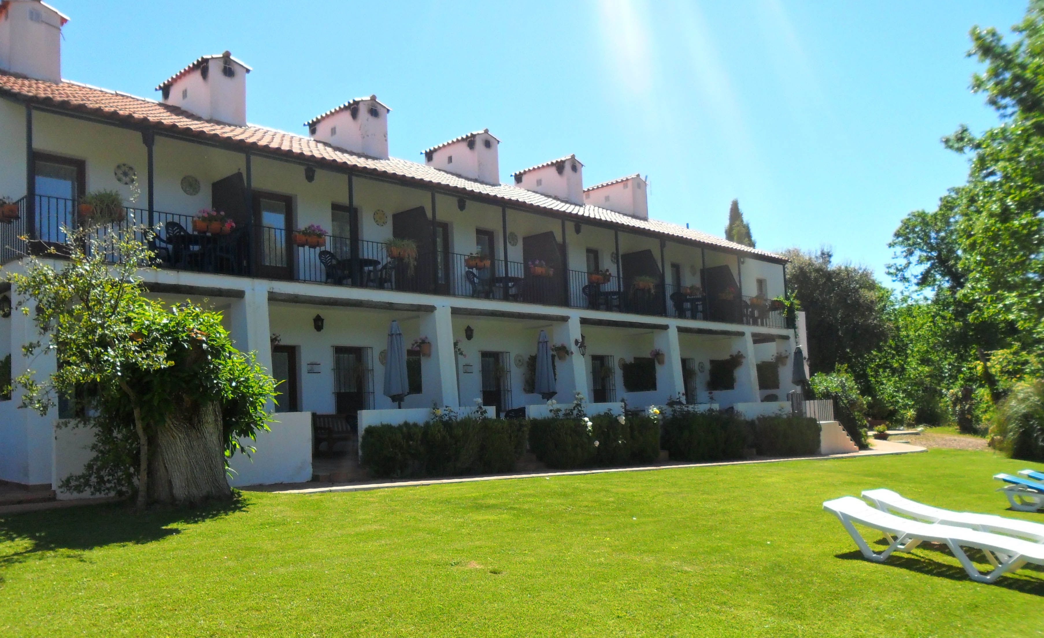 A multi-story hotel with balconies, a well-maintained lawn, and outdoor seating.