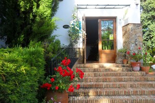 Un edificio con puerta de madera, pared de piedra y una escalera de ladrillo que lleva a la entrada.