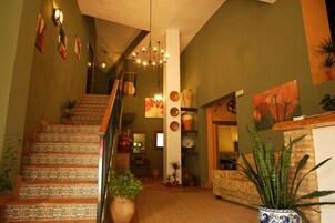Una escalera con baldosas estampadas, un candelabro y varias plantas en macetas.