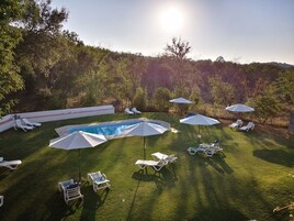 Un patio trasero con piscina, sillas de sol y sombrillas.