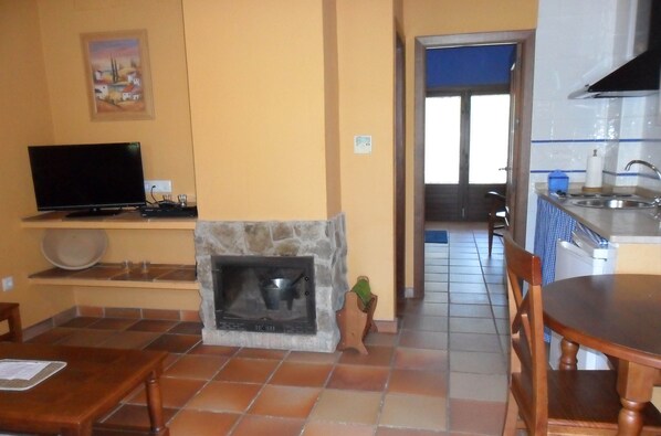 A living room with a fireplace, a television, and a dining area with a table and chairs.