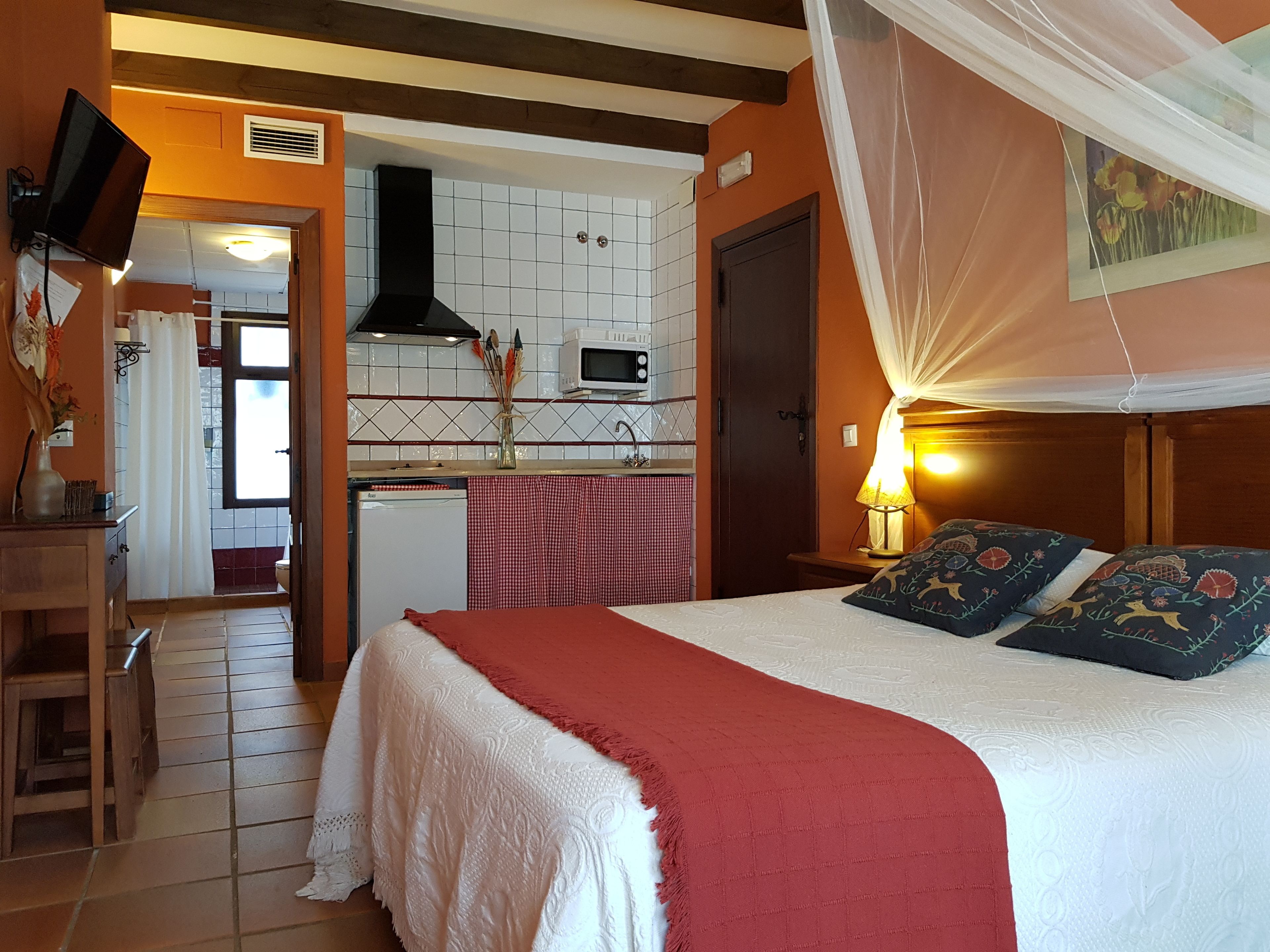 A bedroom with a bed, a nightstand, a lamp, and a canopy.