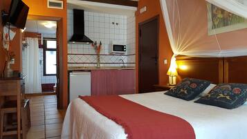 A bedroom with a bed, a nightstand, a lamp, and a canopy.