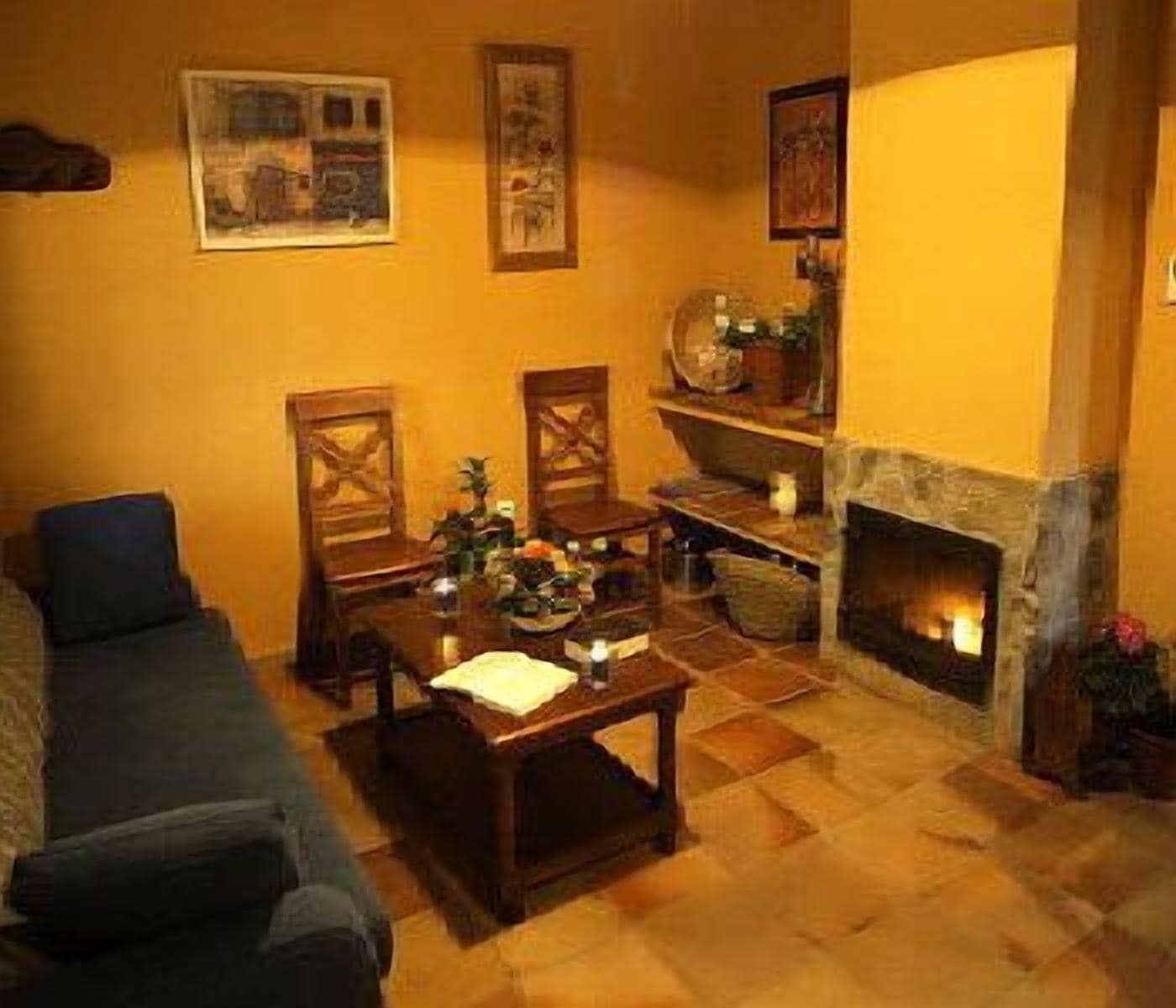 Un salón acogedor con chimenea, un sofá, una mesa de centro y obras de arte colgadas en la pared.