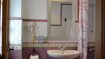 Un baño con lavamanos pedestal, espejo, ducha e inodoro.