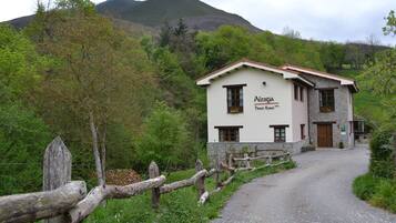 Un edificio de dos pisos con un letrero que dice "Alesga Dosca Rural". Tiene fachada de piedra, una puerta de madera y un camino de grava que conduce a la entrada.