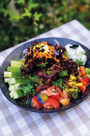 A salad with various vegetables and a white plate on a checkered tablecloth.