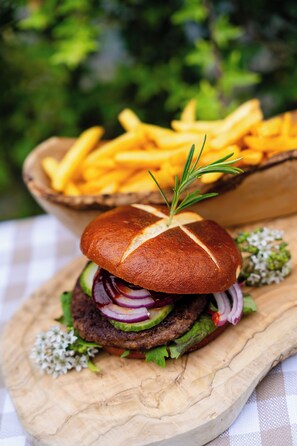 A burger with a bun, lettuce, and red onion on a wooden board.