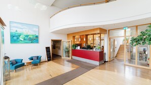 A hotel lobby with a reception desk, seating area, and a staircase. - Klostergasthof Roggenburg (Roggenburg)
