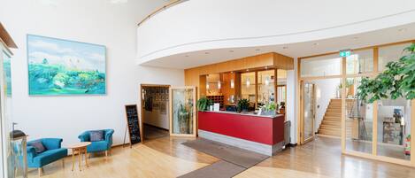 A hotel lobby with a reception desk, seating area, and a staircase.