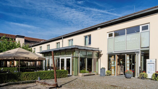 A building with a glass entrance and outdoor seating area. - Klostergasthof Roggenburg (Roggenburg)