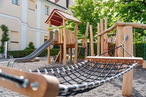 Ein Spielplatz mit Klettergerüst, Rutsche und einer Seilnetzbrücke.