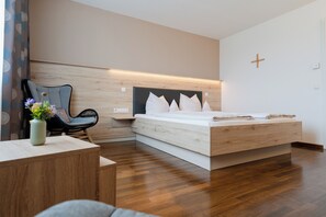 Ein modernes Schlafzimmer mit einem hölzernen Bett, einem Sessel, einem kleinen Tisch und einer Vase mit Blumen.