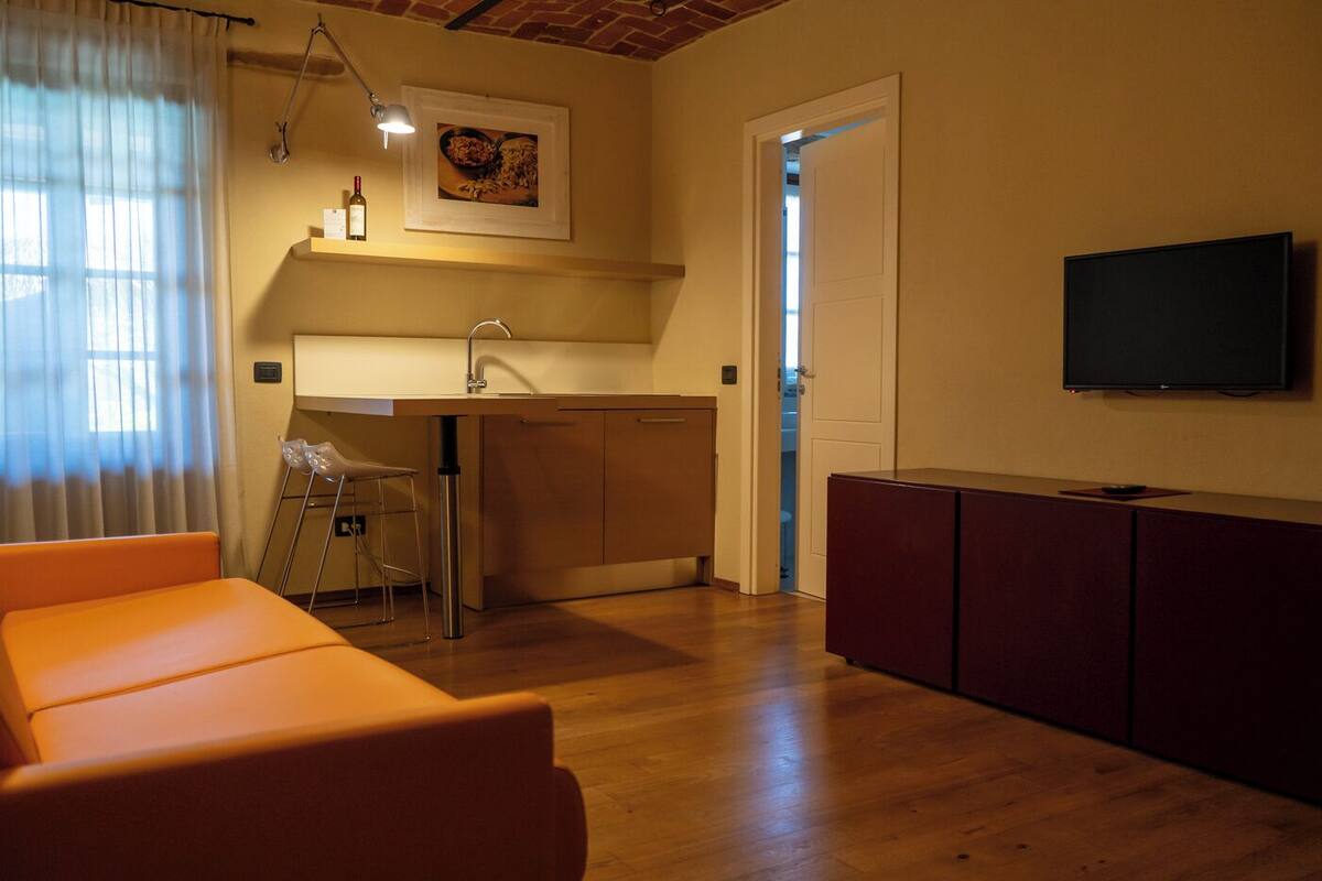 A compact living space with a kitchenette, a dining area, and a TV mounted on the wall.