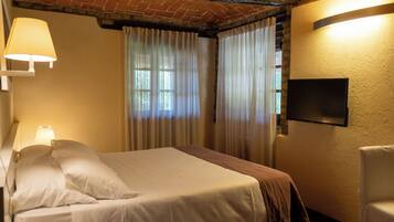 Une chambre d’hôtel avec un lit, une chaise, une télévision et des rideaux.