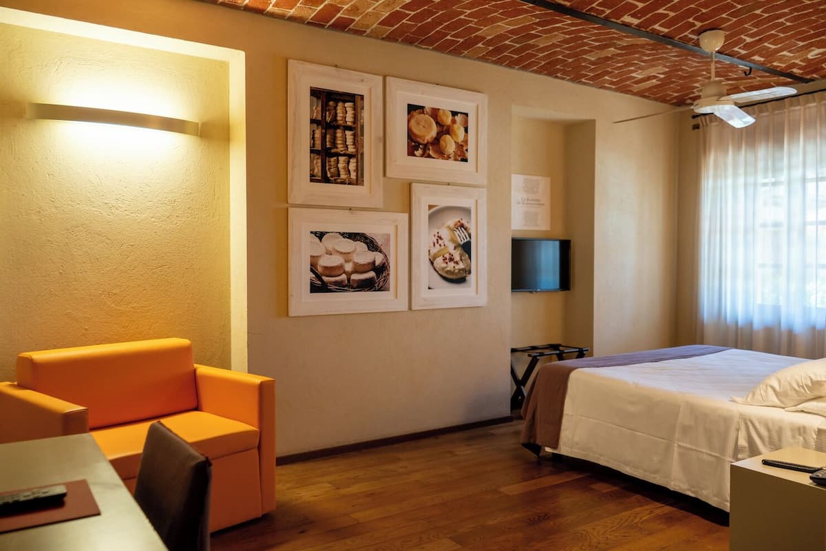 A hotel room with a bed, a desk, a chair, and a television.