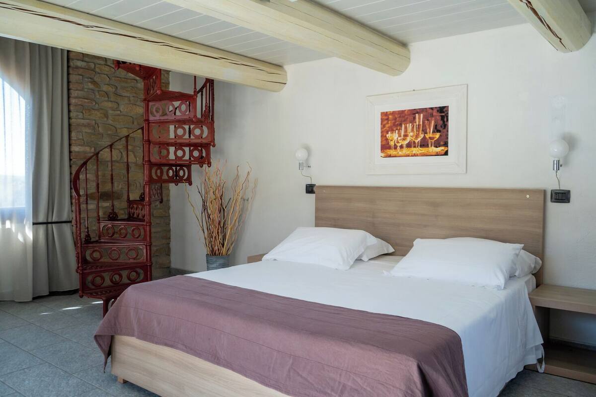 A bedroom with a bed, a wooden headboard, a red spiral staircase, and a wall-mounted picture.