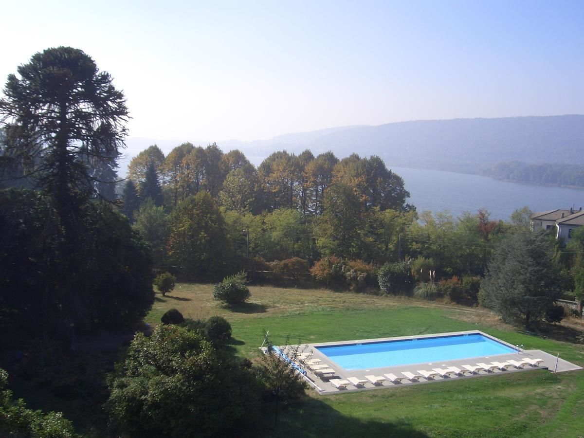 Piscina con sillas de descanso, rodeada de árboles y vista a un lago.