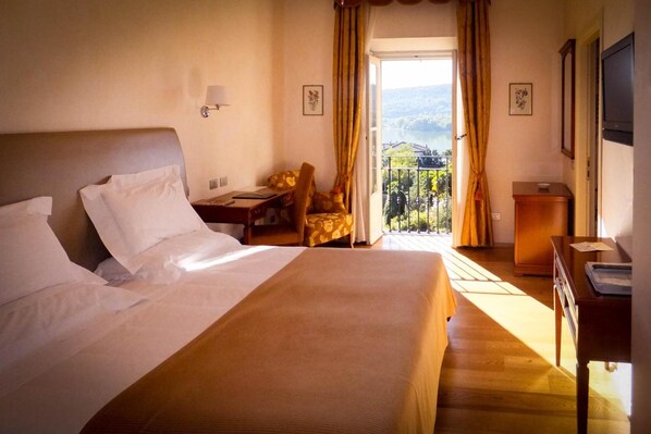 Habitación de hotel con una cama grande, un escritorio, una silla y vistas al exterior.