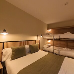 A hotel room with a bunk bed, a single bed, and a nightstand with a lamp. - Marfany (Escaldes-Engordany)