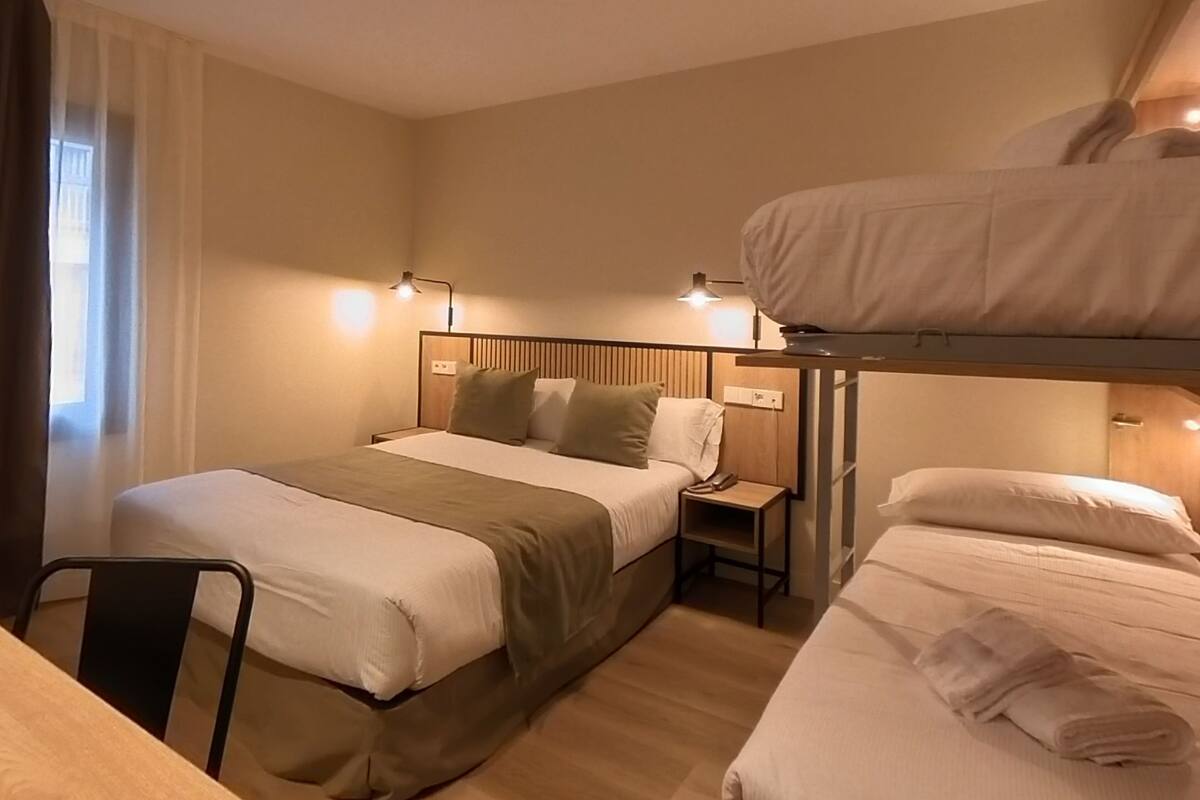 A hotel room with two beds, a desk, and a nightstand.