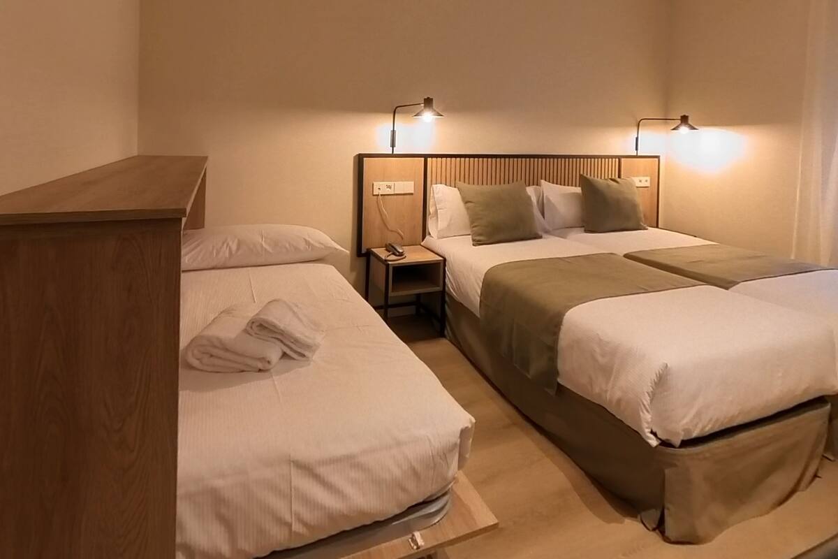 A hotel room with two beds, a wooden desk, and bedside lamps.