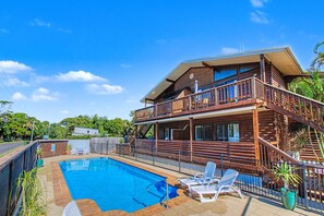 A two-story wooden house with a pool, lounge chairs, and a balcony. - Boat Harbour Stays (Urangan)