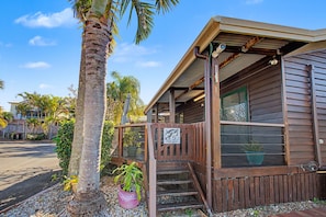 A wooden cabin with a porch, a sign reading 'Villa One,' and a potted plant. - Boat Harbour Apartments (Urangan)