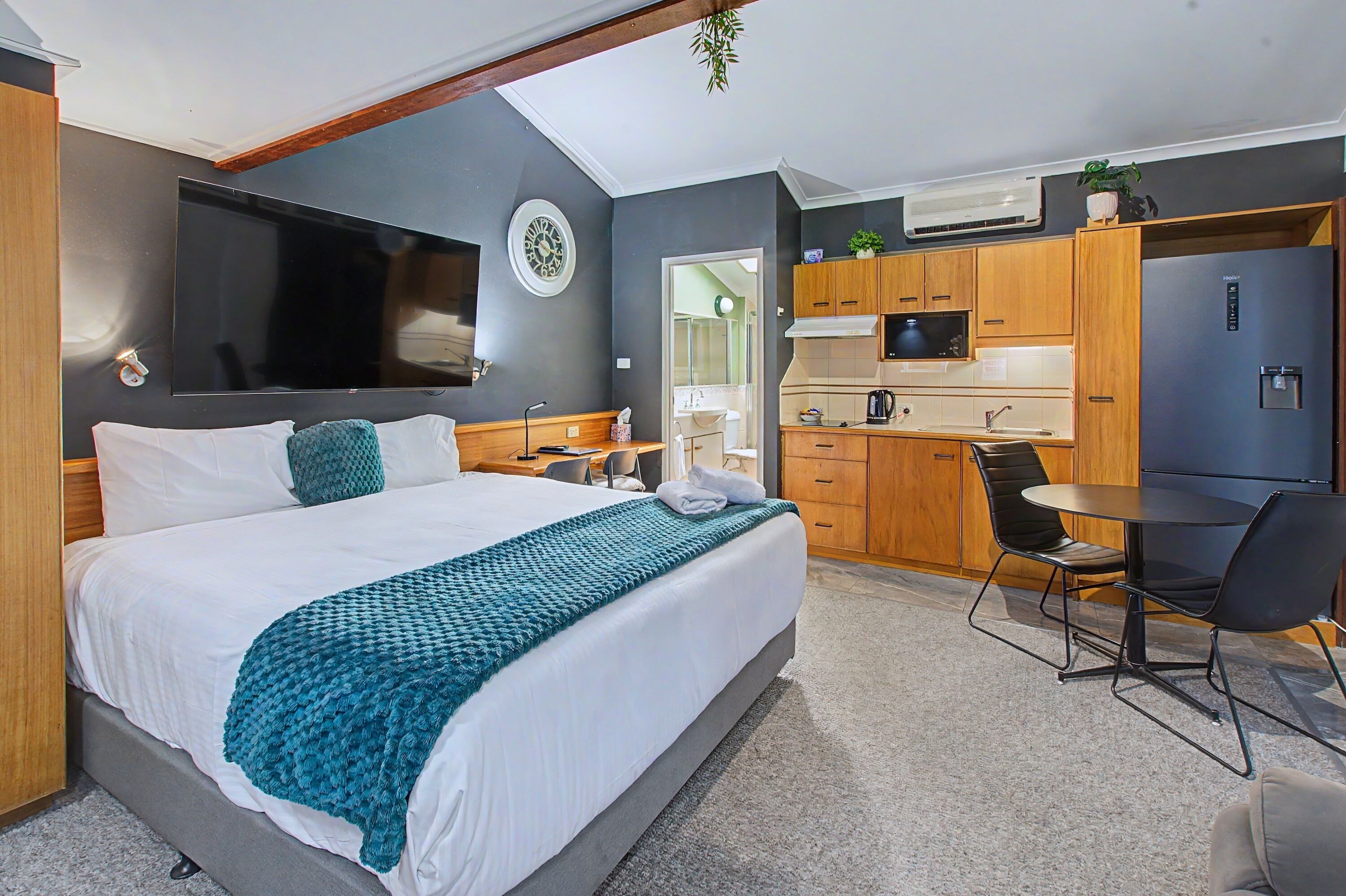 Een moderne slaapkamer met een groot bed, een televisie, een bureau en een kitchenette.