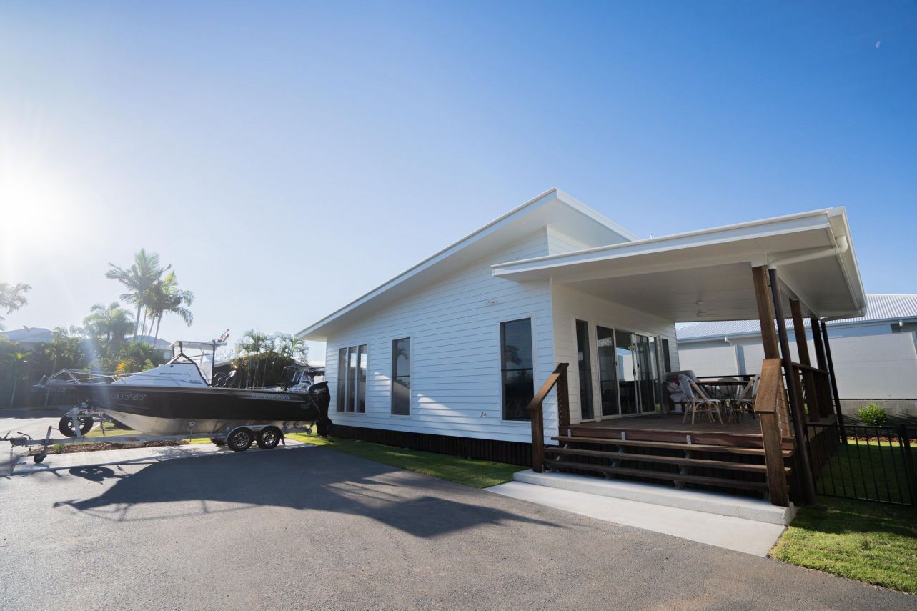 A white house with a covered porch and a boat trailer in the driveway.