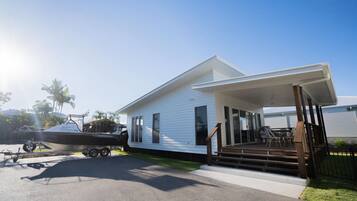A white house with a covered porch and a boat trailer in the driveway.