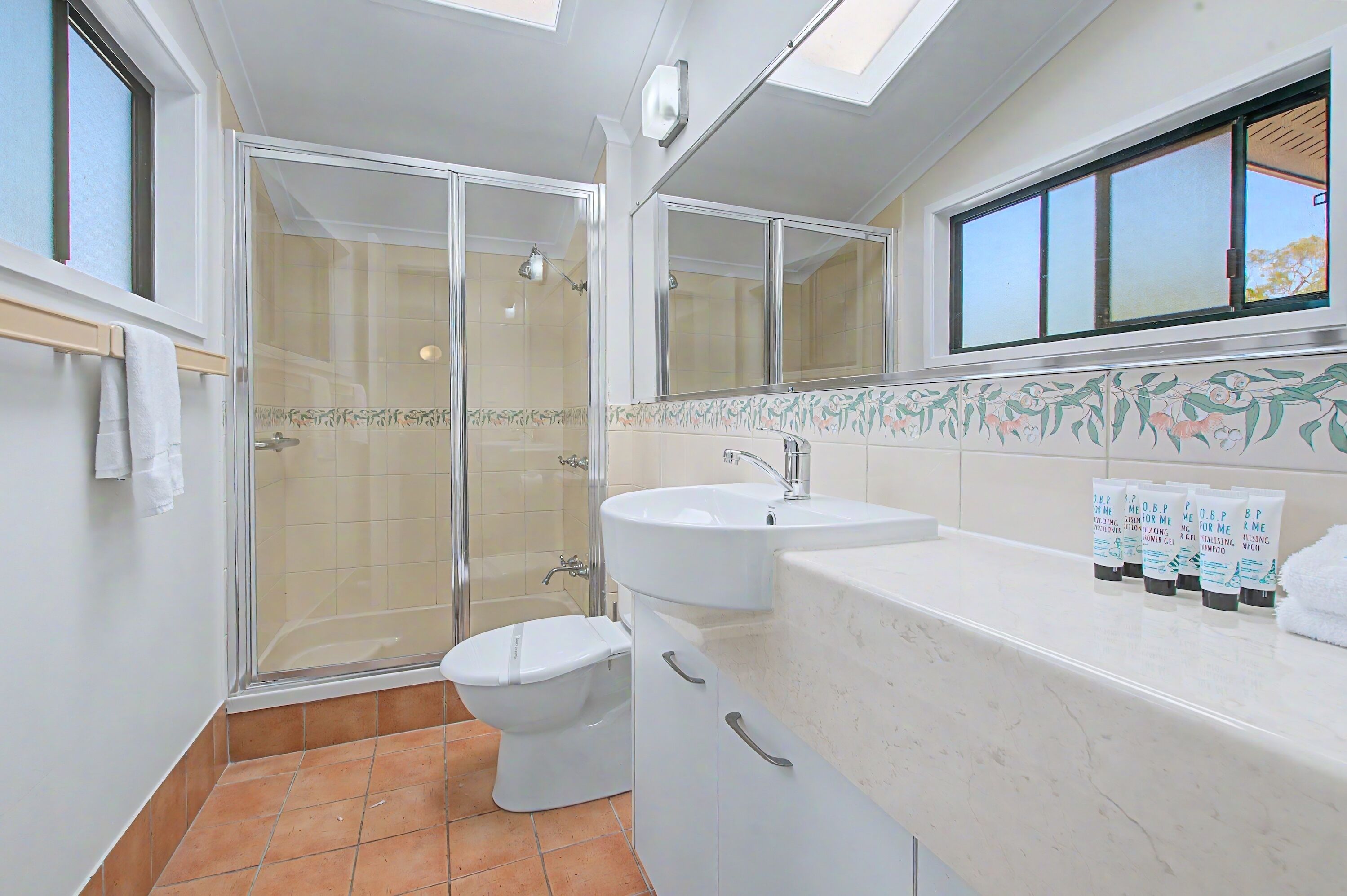 Une salle de bain avec une douche, des toilettes, un lavabo et une fenêtre.