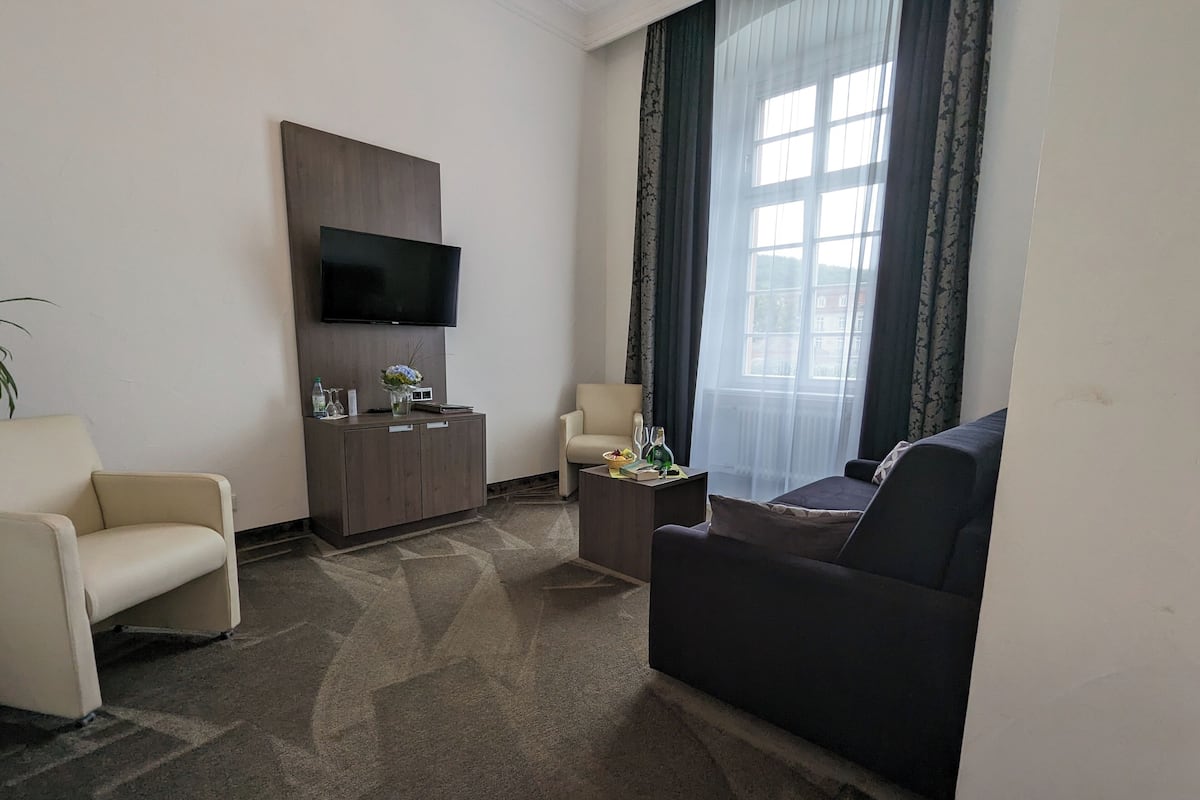 Un salon moderne comprenant un canapé, un fauteuil, une petite table, un meuble et un téléviseur fixé au mur.