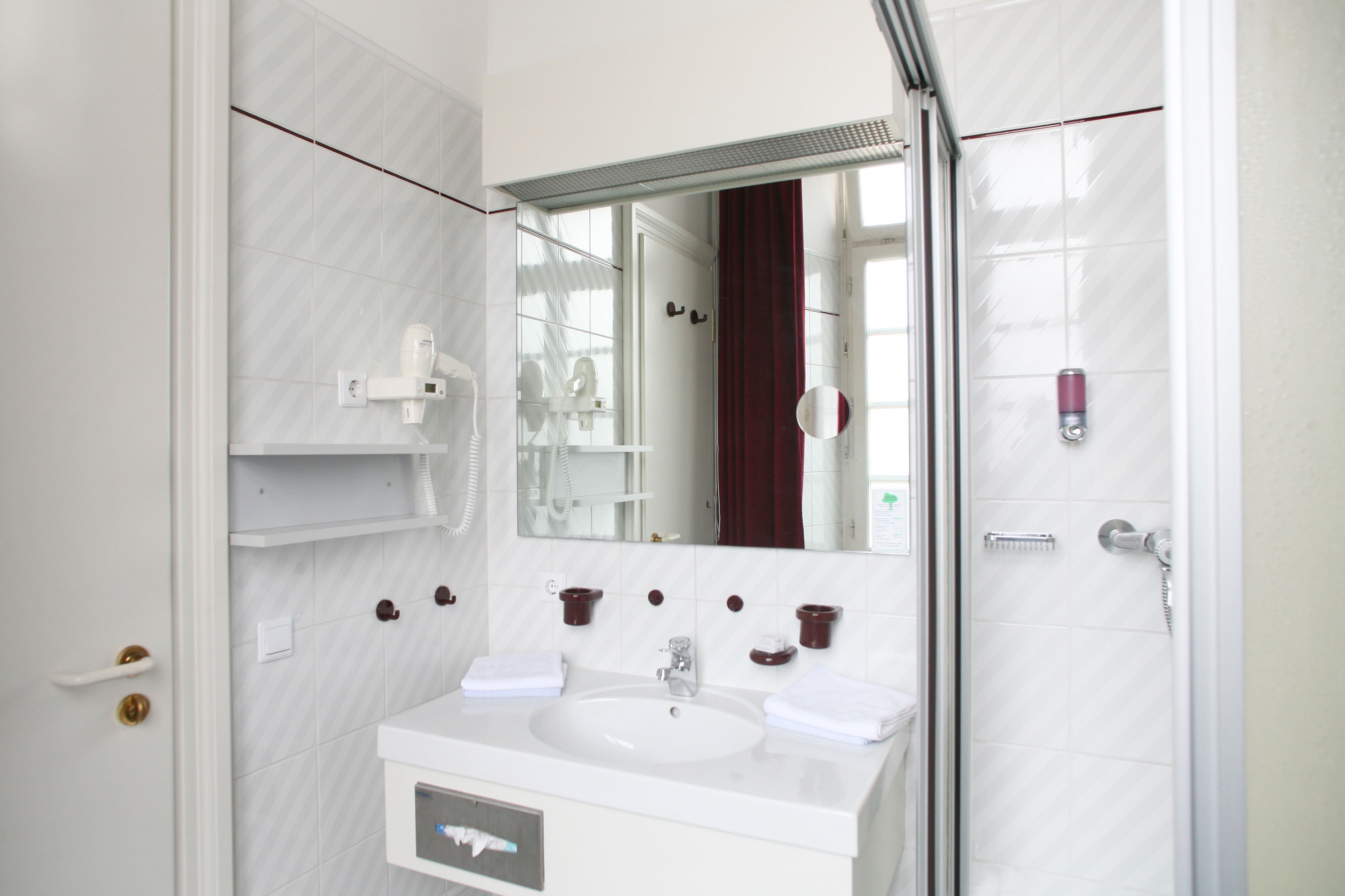 A modern bathroom with a white sink, mirror, and shower.