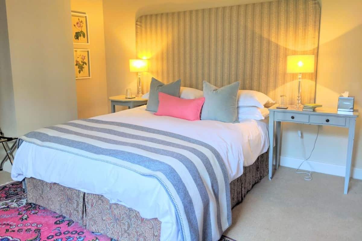 Quarto de hotel bem arrumado com uma cama, duas mesas de cabeceira e uma escrivaninha.
