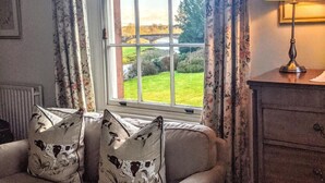 A room with a sofa, a lamp, and a window with curtains. - Warwick Hall (Carlisle)