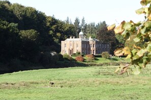 A large, historic building with a symmetrical facade, surrounded by lush greenery and a well-maintained lawn. - Warwick Hall (Carlisle)